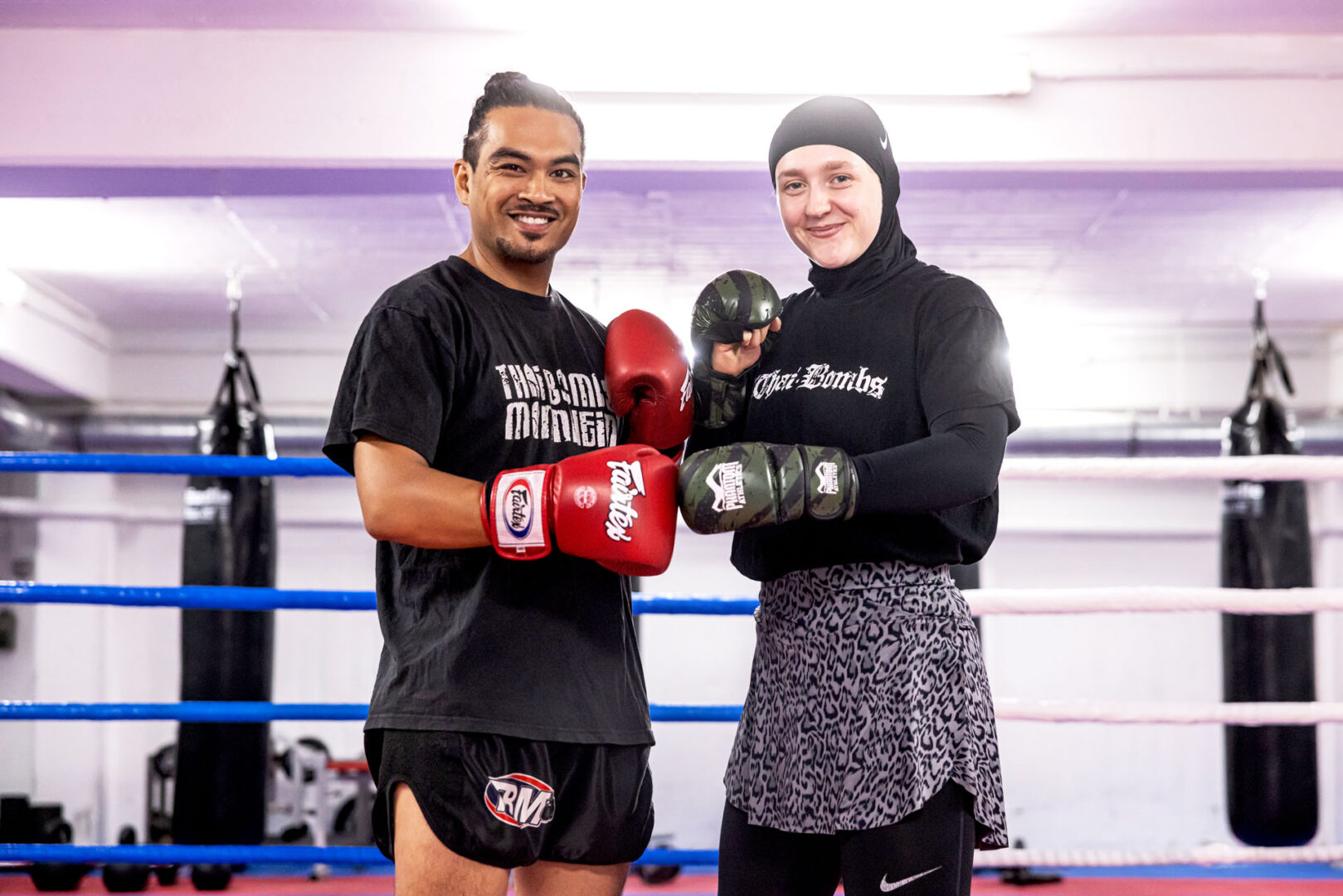 Simon und Malin stehen lächelnd mit Boxhandschuhen nebeneinander im Boxstudio.